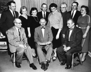 1963 UNA Employees looking at man holding notebook