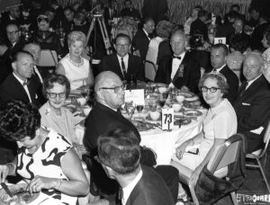 Group of people seated at dinner tables attending a celebration in 1968