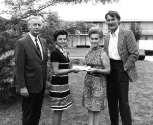 Two UNA Board members delivering a check to a man and a women