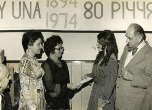 Two women handing another woman and man a check during the 1974 UNA 80th Anniversary